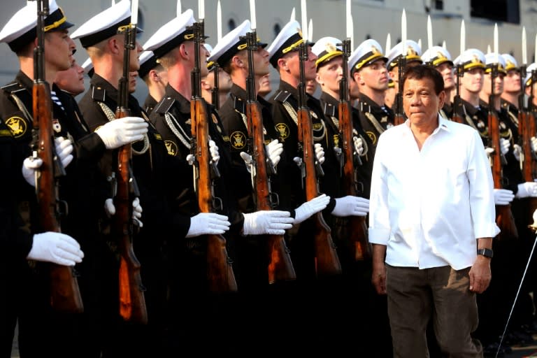 Philippine President Rodrigo Duterte (R) walks past honour guards during a visit to the Russian Guided Missile Cruiser "Varyag” docked at the Port of Manila on April 21, 2017