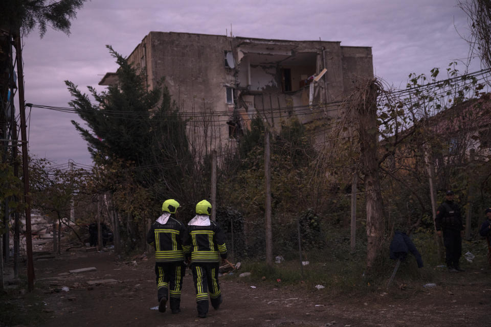 Rescuers from Kosovo walk in front of a damaged building as they participate in a rescue operation in Thumane, western Albania, Wednesday, Nov. 27, 2019. A deadly earthquake struck in the coastal cities of Albania, early Tuesday, killing at least 27 people and injuring more than 650 (AP Photo/Petros Giannakouris)