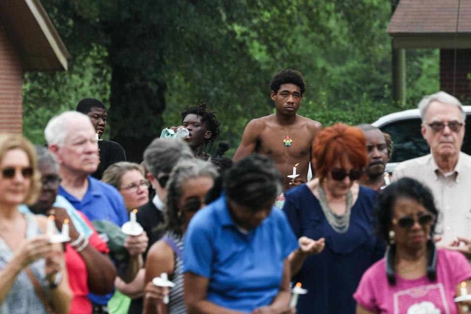 Cristiano Gray, center, holds a candle during a vigil for the lives of three youth lost in an apartment fire on Sunday night at Chapman Homes in Concord, NC. The 17-year-old Gray rushed into the flaming home around midnight. When he did not hear a response, or a sound from a fire alarm, he stumbled outside and called 911.