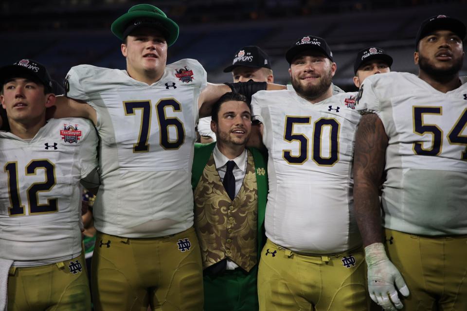 Notre Dame mascot Ryan Coury, center is squeezed between Notre Dame Fighting Irish offensive lineman Joe Alt (76), offensive lineman Rocco Spindler (50) as quarterback Tyler Buchner (12) and offensive lineman Blake Fisher (54) all sing the alma mater song after the game of the TaxSlayer Gator Bowl of an NCAA college football game Friday, Dec. 30, 2022 at TIAA Bank Field in Jacksonville. The Notre Dame Fighting Irish held off the South Carolina Gamecocks 45-38. [Corey Perrine/Florida Times-Union]