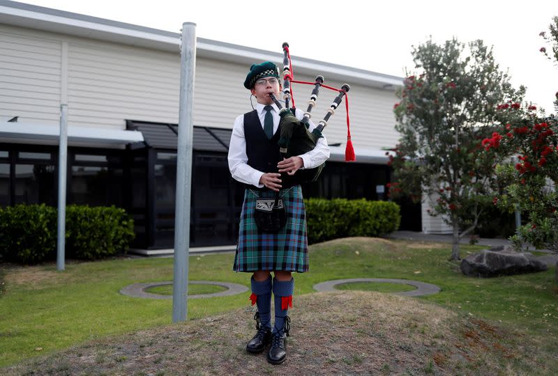 A boy plays bagpipes after a minute of silence for the victims of the White Island volcano eruption, at the hospital in Whakatane