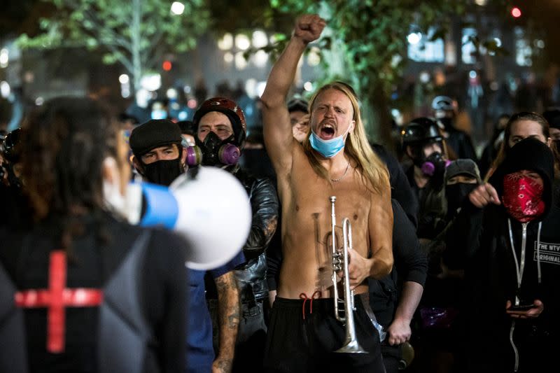 A man holding a trumpet gestures against supporters of U.S. President Donald Trump who drove in a caravan in Portland