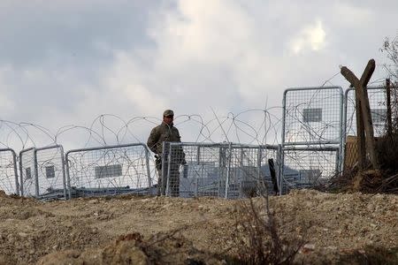 A Turkish soldier standing guard is seen from the Syrian town of Khirbet Al-Joz at the Turkish-Syrian border, in Latakia countryside, where internally displaced Syrian people are waiting to get permission to cross into Turkey, February 7, 2016. REUTERS/Ammar Abdullah