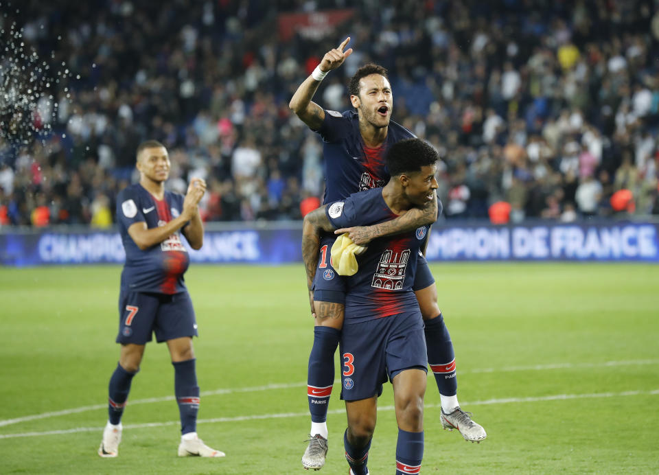 PSG's Neymar, top, sits on the back of PSG's Presnel Kimpembe after the French League One soccer match between Paris-Saint-Germain and Monaco at the Parc des Princes stadium in Paris, Sunday April 21, 2019. PSG were celebrating winning the French League one title. (AP Photo/Michel Euler)