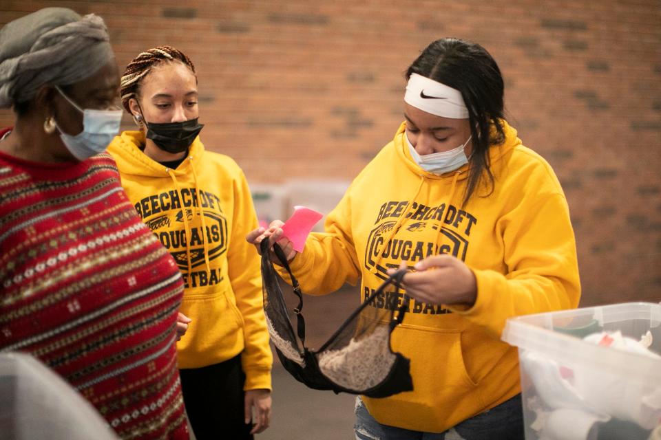 Beechcroft High School seniors, Saraia Fisher, right, and Alese McNair, center, both 17, look for the right-sized bra for Nma Tambedu, 59, at the Church of the Good Shepherd Free Store on Friday.