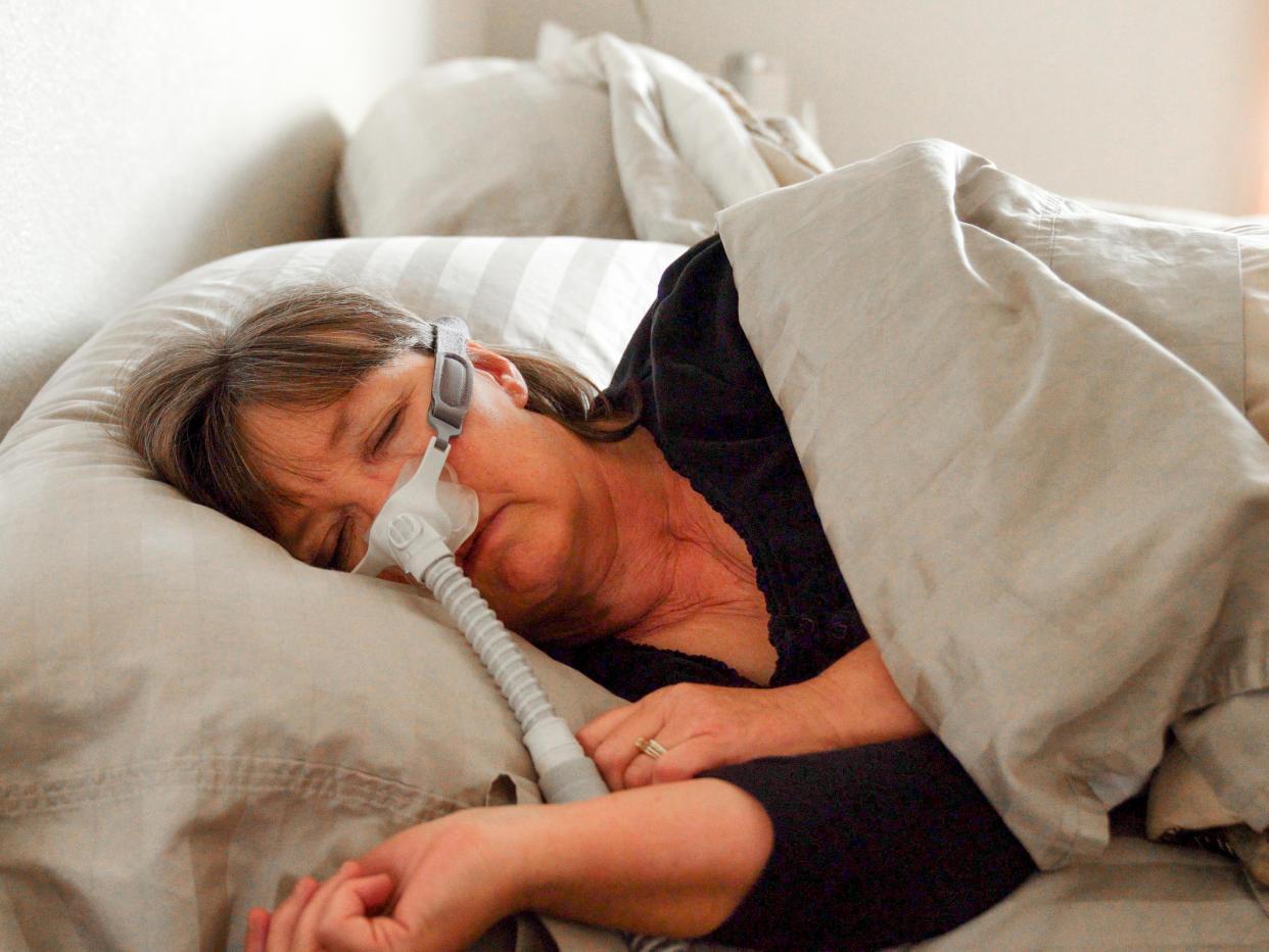 A woman sleeps with a breathing machine to treat sleep apnea.