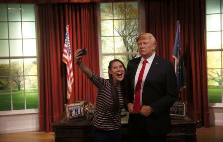 A woman poses with a waxwork of U.S. President-elect Donald Trump during a media event at Madame Tussauds in London, Britain January 18, 2017. REUTERS/Neil Hall