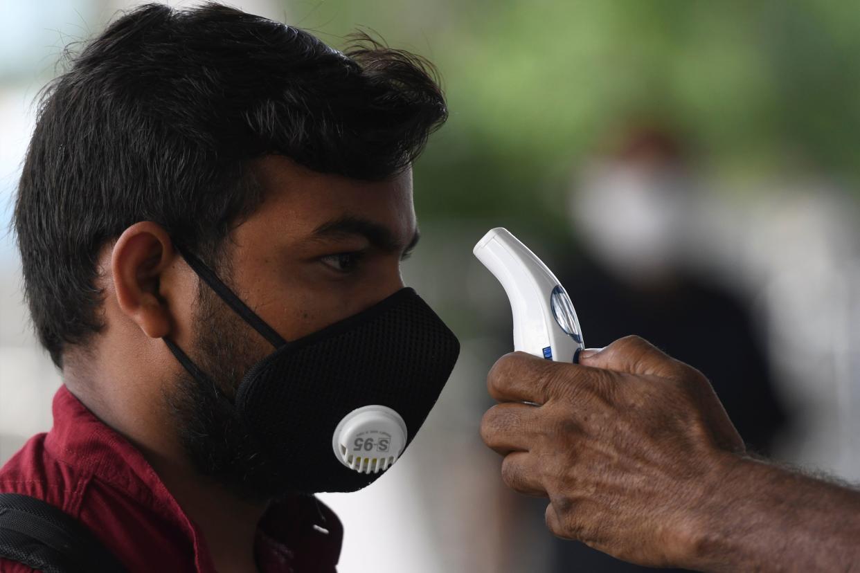 An airport staff checks the temperature of a passenger at the Kamaraj domestic airport during the first day of resuming of domestic flights after the government imposed a nationwide lockdown as a preventive measure against the spread of the COVID-19 coronavirus, in Chennai on May 25, 2020. - Confusion and concern reigned at Indian airports on May 25 as domestic flights tentatively resumed after two months, even as coronavirus cases continued to surge at record rates. (Photo by Arun SANKAR / AFP) (Photo by ARUN SANKAR/AFP via Getty Images)