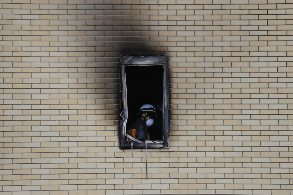 A firefighter is seen through the window of the Kyoto Animation Studio building consumed in an arson attack, Friday, July 19, 2019, in Kyoto, Japan. A man screaming "You die!" burst into the animation studio in Kyoto, doused it with a flammable liquid and set it on fire Thursday, killing dozens of people in the attack that shocked the country and brought an outpouring of grief from anime fans. (AP Photo/Jae C. Hong)