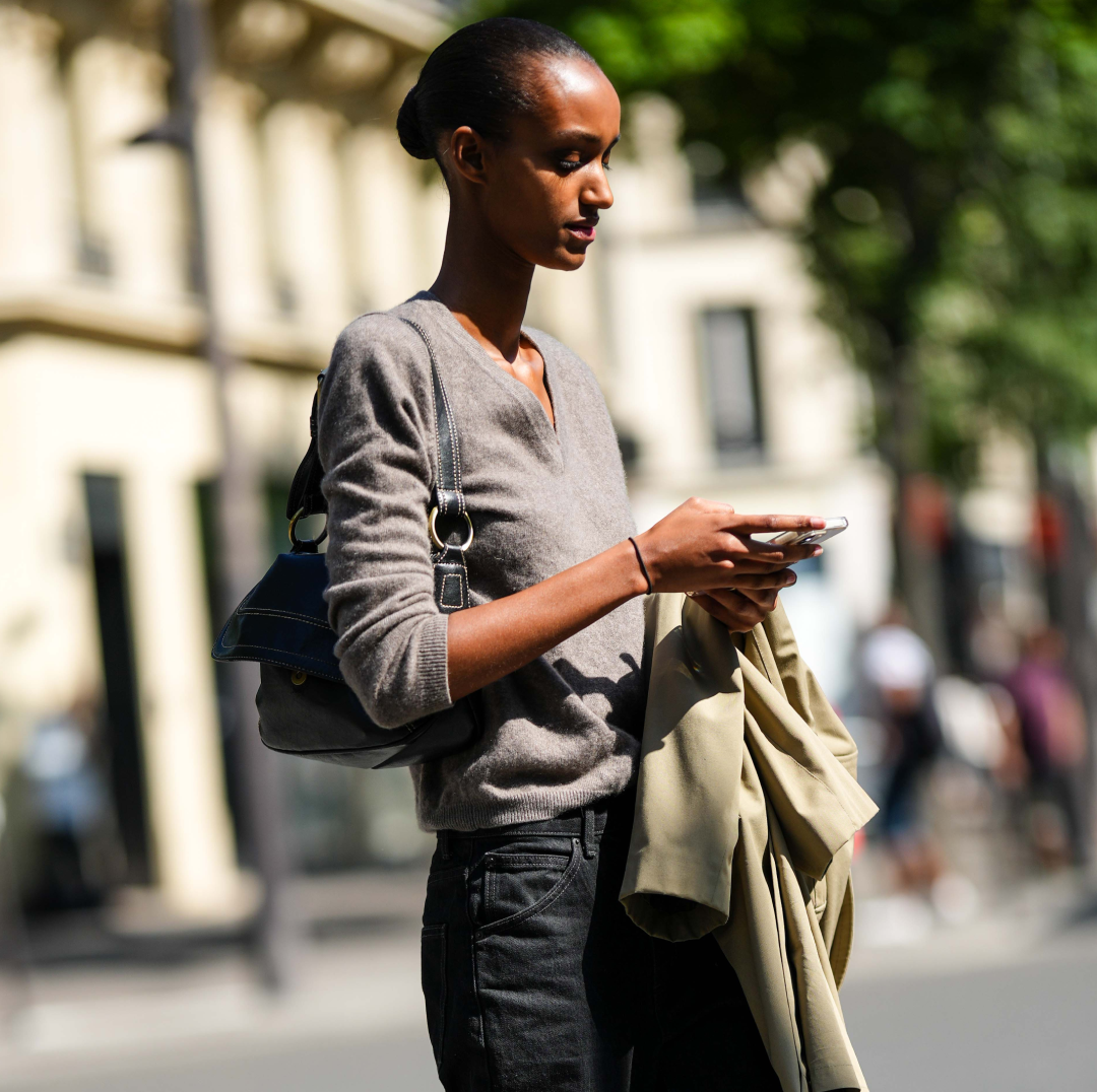  A guest wears a beige wool pullover, a black shiny leather shoulder bag, a beige blazer jacket, black denim large pants, black suede and fabric sneakers , outside Ashi Studio, during the Haute Couture Fall/Winter 2023/2024 as part of Paris Fashion Week on July 06, 2023 in Paris, France. 