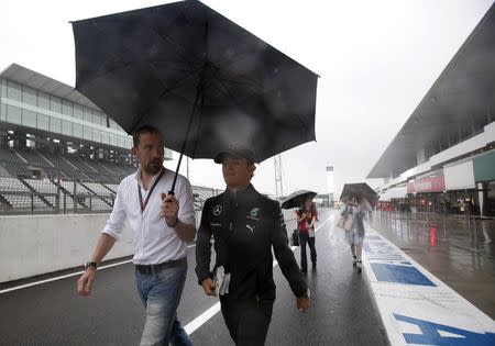 Mercedes Formula One driver Nico Rosberg of Germany walks down the pit, ahead of a fan taking photos of him, at the Suzuka circuit in Suzuka, western Japan, October 2, 2014, ahead of Sunday's Japanese F1 Grand Prix. REUTERS/Yuya Shino