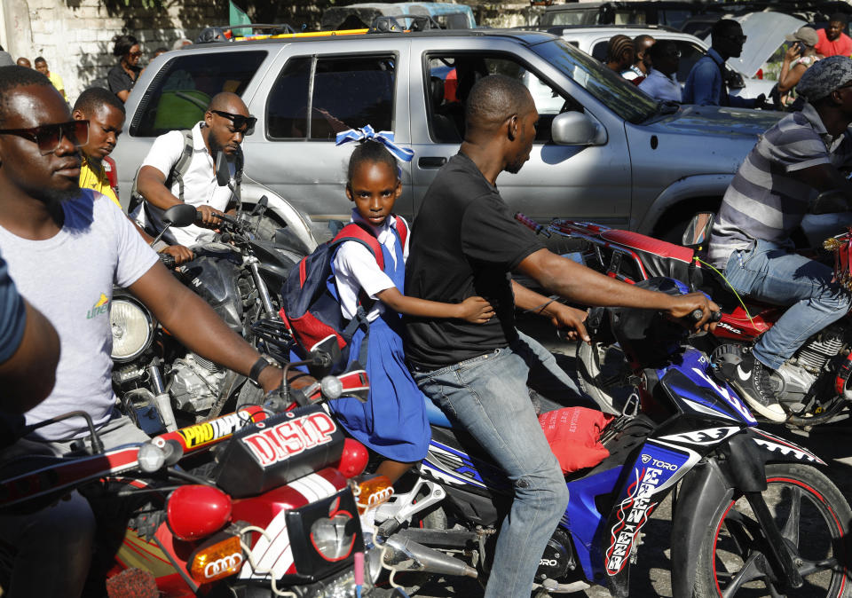 Moto-taxi drivers wait to cross a barricade constructed by protesters to call attention to the country's insecurity and demanding the resignation of the prime minister, in Port-au-Prince, Haiti, Thursday, Jan. 18, 2024. (AP Photo/Odelyn Joseph)