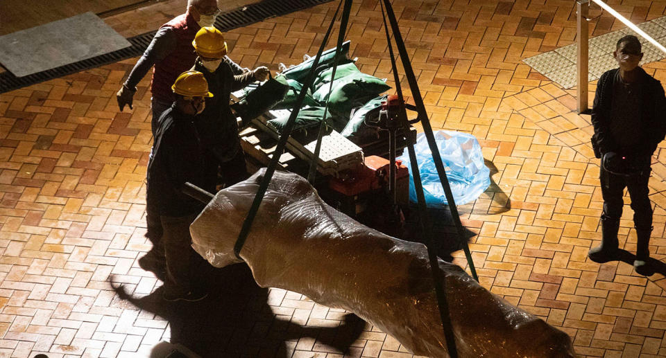 Workers remove the Pillars of Shame monument.