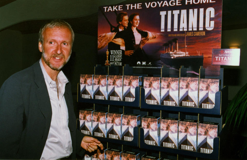 James Cameron, producer, director, and writer of the hit movie Titantic, stands next to a display of Titantic home videos during a press conference, June 8 in Los Angeles, announcing the September 1, 1998 videocassette availability of the Paramount Pictures film. Paramount Pictures plans to spend $50 million promoting the video, $10 million more than was spend promoting the film version.