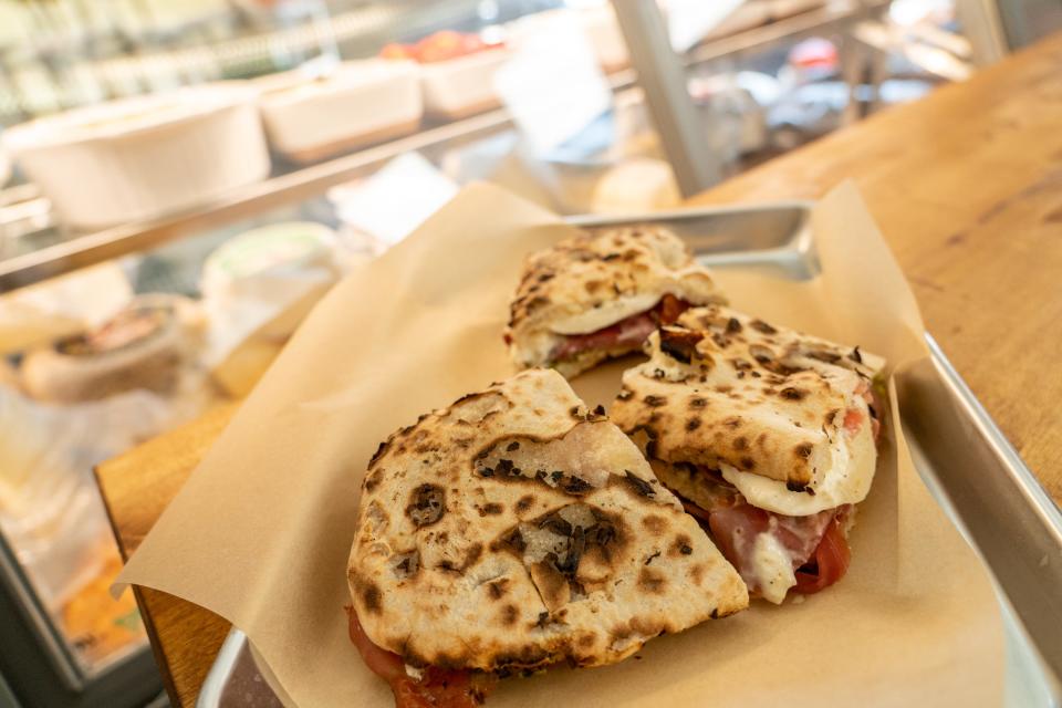 A panini made with homemade dough, 18-month-aged prosciutto di Parma, pistachio pesto, burrata, pecorino spread and an olive oil drizzle is displayed at Fabio on Fire Panini and Gelateria in Peoria on June 13, 2023.