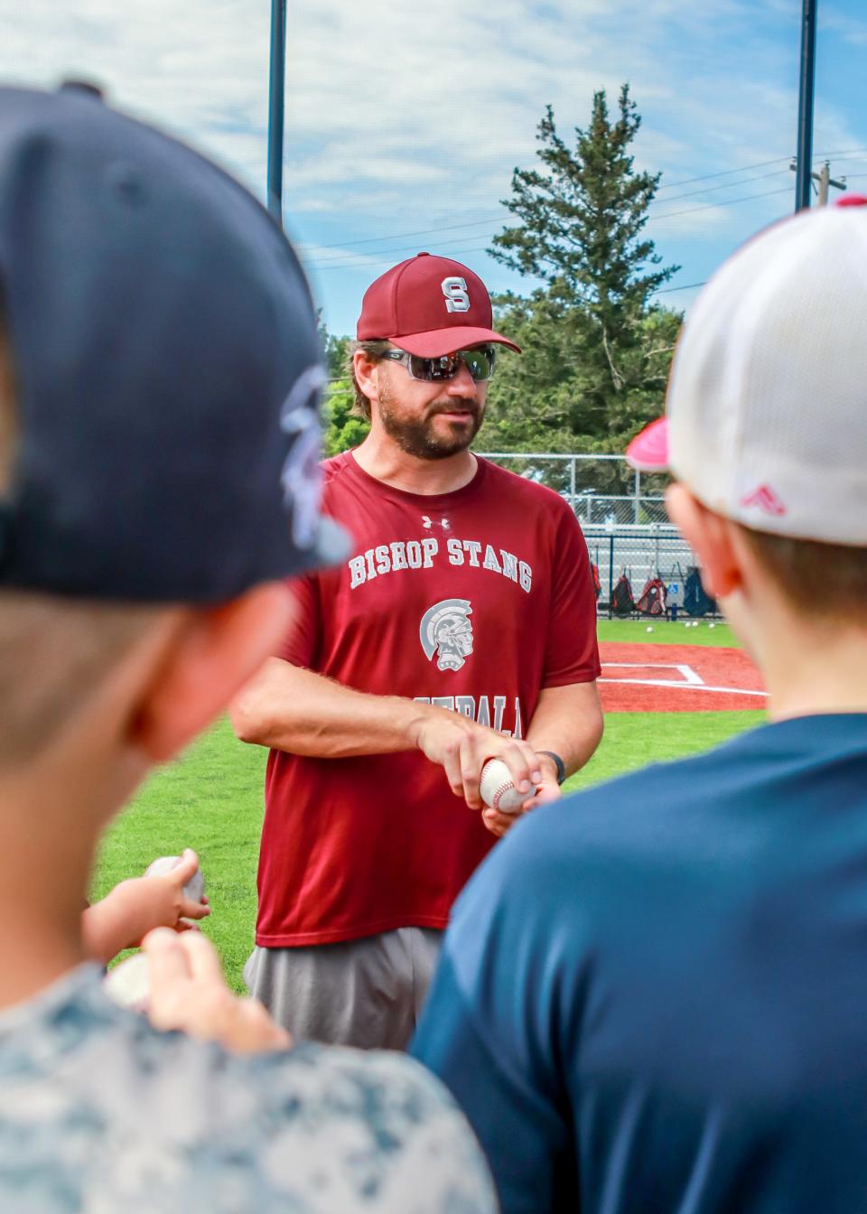 Brian Rose discusses proper grips with pitchers at one of the pitching stations during the Stang Summer Baseball Clinic.