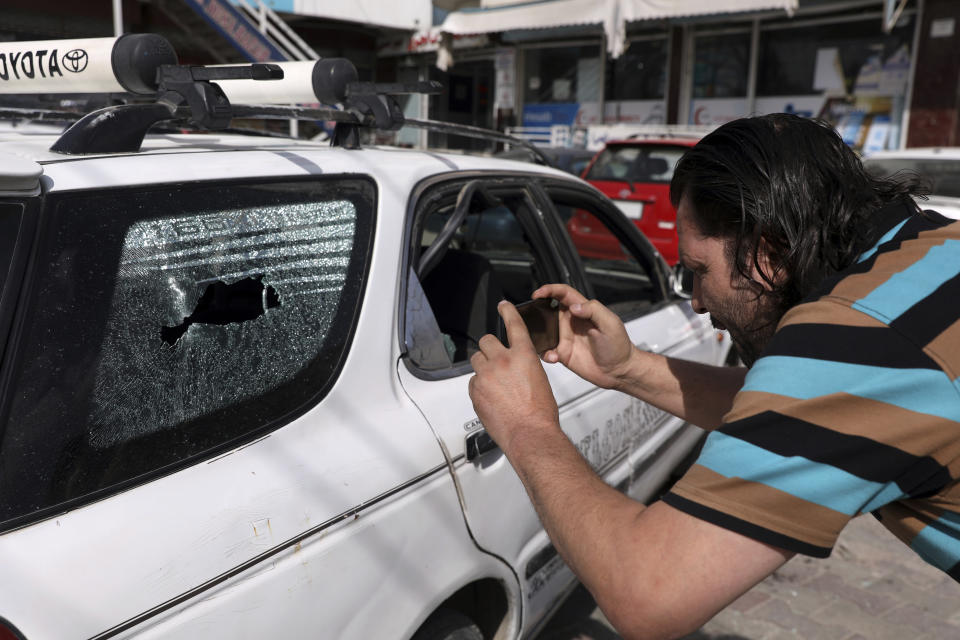 An Afghan journalist films the vehicle in which director of Afghanistan's Government Information Media Center Dawa Khan Menapal was shot dead in Kabul, Afghanistan, Friday, Aug. 6, 2021. The Taliban shot and killed the director of Afghanistan's Government Information Media Center on Friday, the latest killing of a government official and one that comes just days after an assassination attempt on the acting defense minister. (AP Photo/Rahmat Gul)