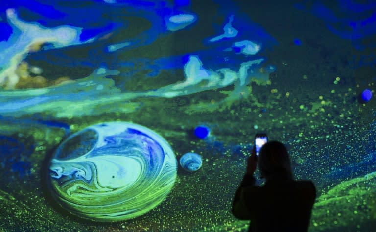 A woman takes a photo of the Kingdom of Colors exhibition, an immersive visual experience from French filmmaker Thomas Blanchard and artist Oilhack in Washington DC