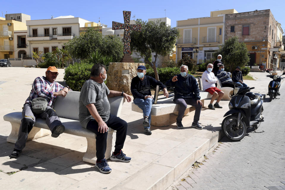 Residents sit on benches at Vittorio Garibaldi Square, on the Island of Lampedusa, southern Italy, Wednesday, May 12, 2021. Lampedusa is closer to Africa than the Italian mainland, and it has long been the destination of choice for migrant smuggling operations leaving Libya. Over the years, it has witnessed countless numbers of shipwrecks and seen bodies floating offshore, only to be buried in the cemetery on land. (AP Photo/Salvatore Cavalli)