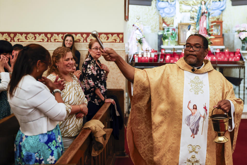 Father Ako Walker sprinkles holy water on parishioners during Easter Mass at Sacred Heart of Jesus and Saint Patrick, Sunday, March 31, 2024, in Baltimore, Md. (AP Photo/Julia Nikhinson)