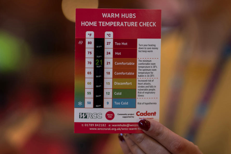 A staff member of the Warwickshire Rural Community Council, holds a leaflet of temperature check, at the Other Place theater, in Stratford-upon-Avon, Warwickshire, England, Tuesday, Feb. 28, 2023. The foyer of the Other Place theater in Shakespeare's birthplace of Stratford-upon-Avon is a cozy refuge from winter. One day a week the theater becomes a "warm hub," set up by the Royal Shakespeare Company to welcome people who may be struggling to heat their homes because of sky-high energy prices. (AP Photo/Kin Cheung)