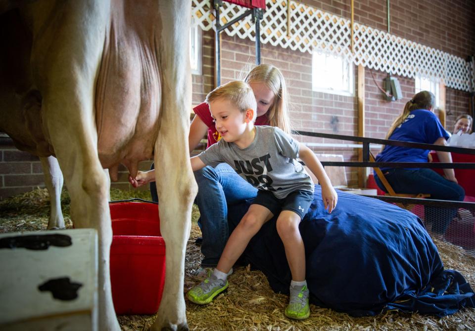 In 2021, Zayd Hodzic of Grimes learned to milk a cow from Iowa State University sophomore Abigail Rogers at the Iowa State Fair.