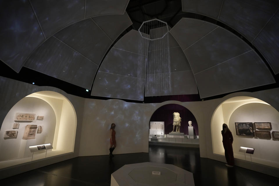 Museum employees pose for photographers in a display area to tell the story of Roman emperor Nero's grand palace, called the Domus Aurea (Golden House), which was finished by Nero's death in AD 68, during a media preview for the "Nero: the man behind the myth" exhibition, at the British Museum in London, Monday, May 24, 2021. The exhibition, which open to visitors on May 27 and runs until October 24, explores the true story of Rome's fifth emperor informed by new research and archaeological evidence from the time. (AP Photo/Matt Dunham)