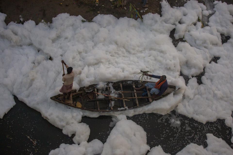 A man rows a boat in Yamuna River, covered by a chemical foam caused by industrial and domestic pollution, during the Chhath Puja festival in New Delhi, India, Wednesday, Nov. 10, 2021. A vast stretch of one of India's most sacred rivers, the Yamuna, is covered with toxic foam, caused partly by high pollutants discharged from industries ringing the capital New Delhi. Still, hundreds of Hindu devotees Wednesday stood knee-deep in its frothy, toxic waters, sometimes even immersing themselves in the river for a holy dip, to mark the festival of Chhath Puja. (AP Photo/Altaf Qadri)