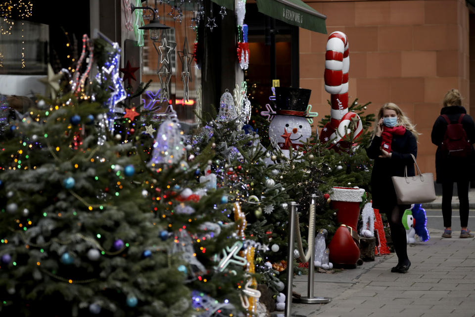 A woman walks past a Christmas decorations display outside a wine shop in Mayfair, London, Wednesday, Dec. 16, 2020. London and some of its surrounding areas have been placed under Britain's highest level of coronavirus restrictions beginning at 00:01 local time on Wednesday as infections rise rapidly in the capital. Under Tier 3 restrictions, the toughest level in England's three-tier system, people can't socialize indoors, and bars, pubs and restaurants must close except for takeout. (AP Photo/Matt Dunham)