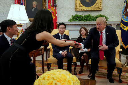 U.S. President Donald Trump is presented a book "The Girl with Seven Names" during his meeting with North Korean defectors in the Oval Office of the White House in Washington, U.S., February 2, 2018. REUTERS/Yuri Gripas