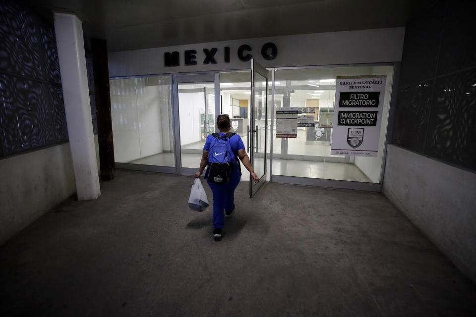 Dulce Garcia carries groceries as she makes her way home to Mexico after work Wednesday, July 22, 2020, in Calexico, Calif. (AP Photo/Gregory Bull)