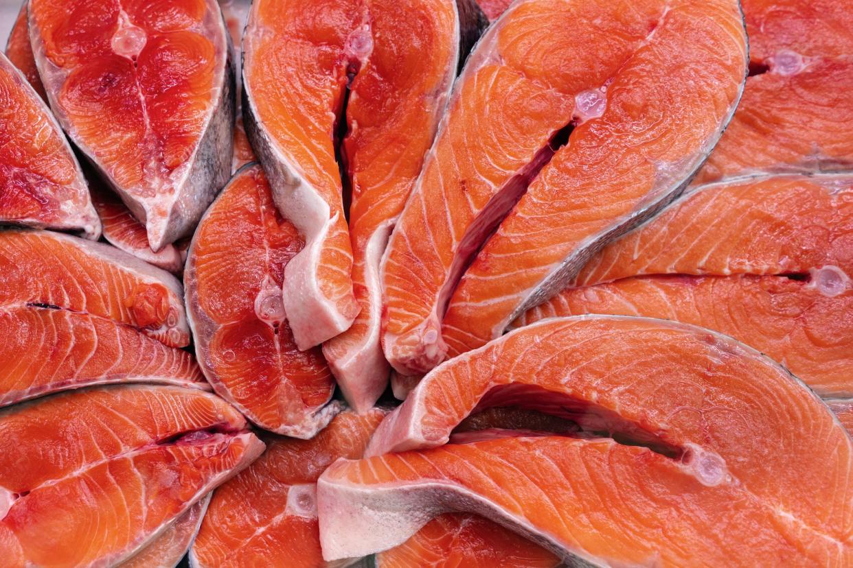 Lot of pieces raw Pacific Red Fish Chinook Salmon cut into steak and ready for cooking various delicious dishes. Close-up flat lay view of fresh wild fish King Salmon - delicacy Asian cuisine.