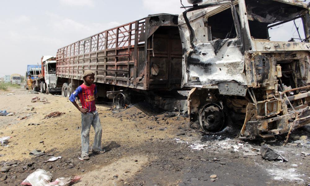 A Yemeni boy stands next to burnt trucks following a reported airstrike by the Saudi-led coalition in the Hays District of the province of Hodeidah.