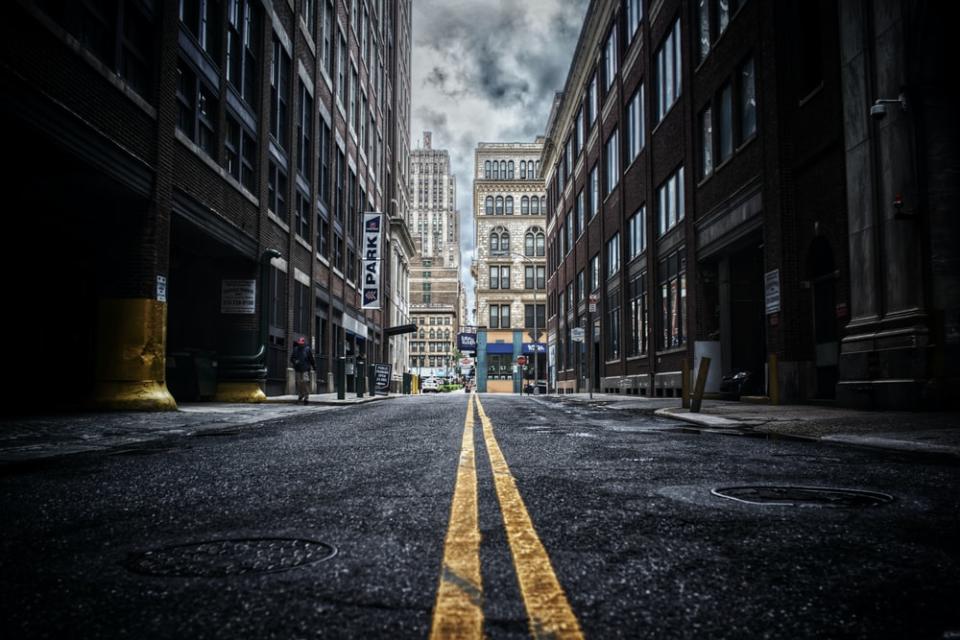 low-angle photo of street between two brown concrete buildings