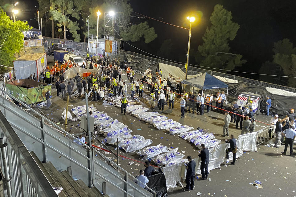 Israeli security officials and rescuers stand around the bodies of victims who died during a Lag Ba'Omer celebrations at Mt. Meron in northern Israel, Friday, April 30, 2021. The director of an Israeli ambulance service has confirmed that nearly 40 people died in a stampede at a religious festival in northern Israel. (Ishay Jerusalemite/Behadrei Haredim via AP)