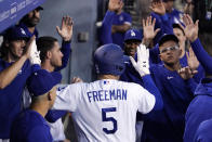 Los Angeles Dodgers' Freddie Freeman is congratulated by teammates in the dugout after hitting a solo home run during the first inning of a baseball game against the Atlanta Braves Monday, April 18, 2022, in Los Angeles. (AP Photo/Mark J. Terrill)