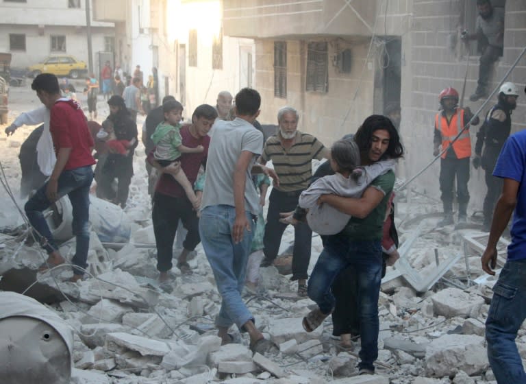 Men carry injured people through the rubble of destroyed buildings following a reported air strike on the rebel-held northwestern Syrian city of Idlib on September 29, 2016