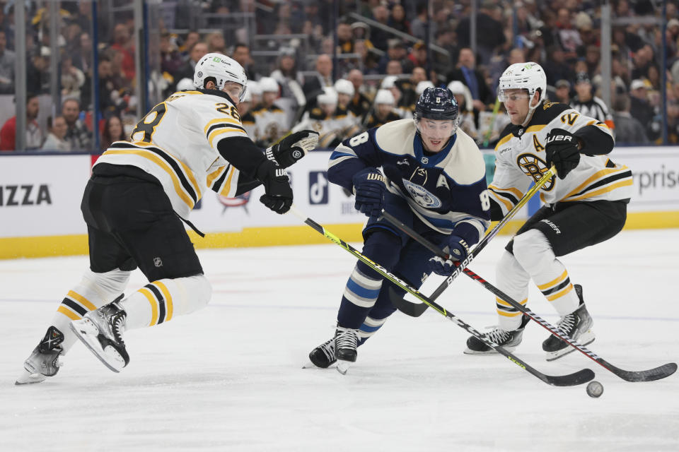 Columbus Blue Jackets' Zach Werenski, center, skates between Boston Bruins' Derek Forbort, left, and Brandon Carlo during the second period of an NHL hockey game Friday, Oct. 28, 2022, in Columbus, Ohio. (AP Photo/Jay LaPrete)