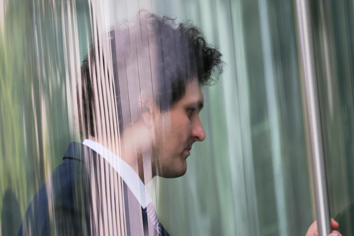 Former FTX CEO Sam Bankman-Fried, photographed from the side through a pane of glass.