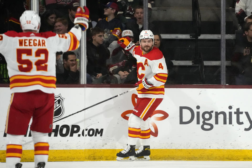 Calgary Flames defenseman Rasmus Andersson (4) celebrates after his goal against the Arizona Coyotes as Flames defenseman MacKenzie Weegar (52) skates in during the first period of an NHL hockey game Thursday, Jan. 11, 2024, in Tempe, Ariz. (AP Photo/Ross D. Franklin)