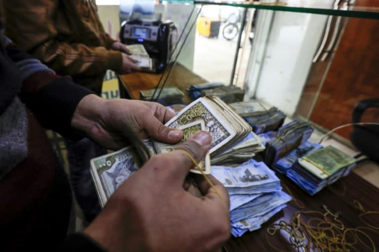 Currency exchange employees count banknotes in the northeastern Syrian town of Qamishli on May 2, 2018