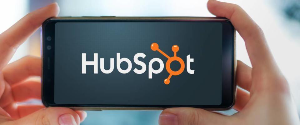 Hands holding smartphone displaying logo of HubSpot, an American developer and marketer of software products for inbound marketing, sales, and customer service