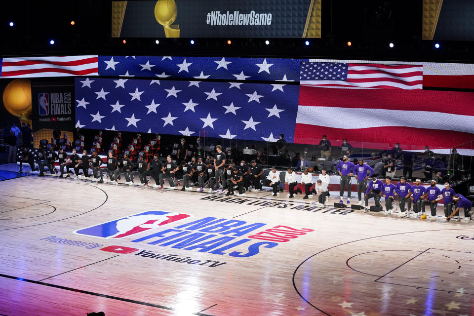 The Los Angeles Lakers and Miami Heat are seen on the court during the national anthem before Game 3 of basketball's NBA Finals, Sunday, Oct. 4, 2020, in Lake Buena Vista, Fla. (AP Photo/Mark J. Terrill)