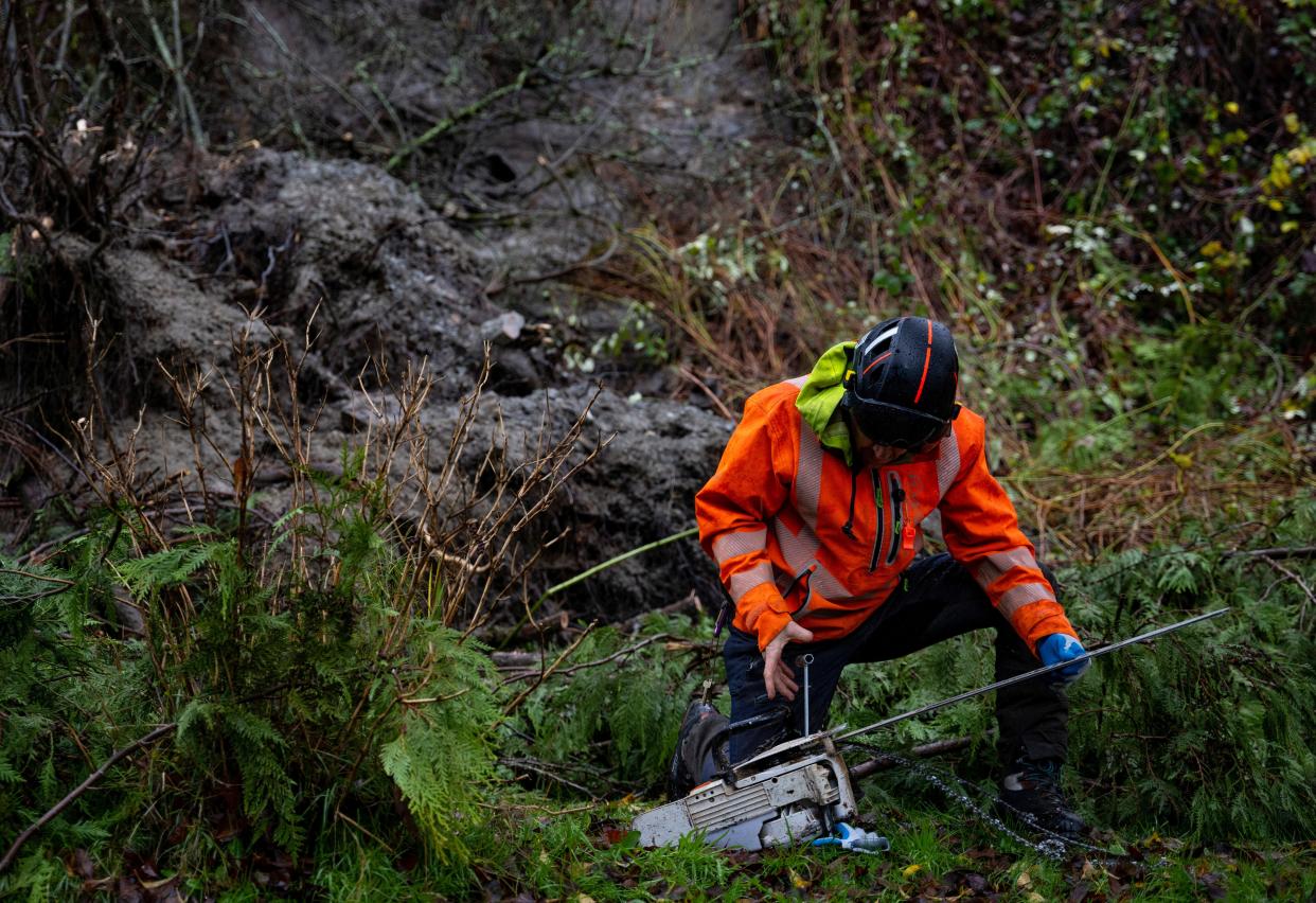 Seattle Parks and Recreation respond to a landslide Tuesday on Burke-Gilman Trail in Seattle. An atmospheric river is bringing heavy rain, flooding and warm winter temperatures to the Pacific Northwest. The National Weather Service on Tuesday issued a flood warning for parts of western Washington.