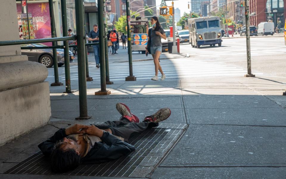 A person lays on a subway exhaust vent during a heatwave in New York - Bloomberg