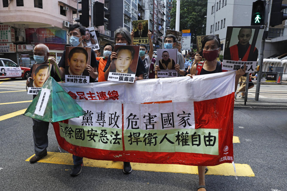 Pro-democracy demonstrators hold up a banner and portraits of jailed Chinese civil rights activists, lawyers and legal activists as they march to the Chinese liaison office in Hong Kong, Thursday, June 25, 2020. The banner read "One-party dictatorship harms the country, abolish the national security law and defend human rights and freedom in Hong Kong". (AP Photo/Kin Cheung)