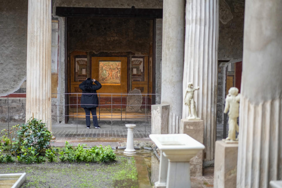 A woman takes pictures of the "triclinium", or dining room, called Hall of Pentheus, part of the Ancient Roman Domus Vettiorum, House of Vettii, in the Pompeii Archeological Park, near Naples, southern Italy, Wednesday, Dec. 14, 2022. One of Pompeii's most famous and richest domus, which contains exceptional works of art and tells the story of the social ascent of two former slaves, is opening its doors to visitors Wednesday, Jan. 11, 2023 after 20 years of restoration. (AP Photo/Andrew Medichini)