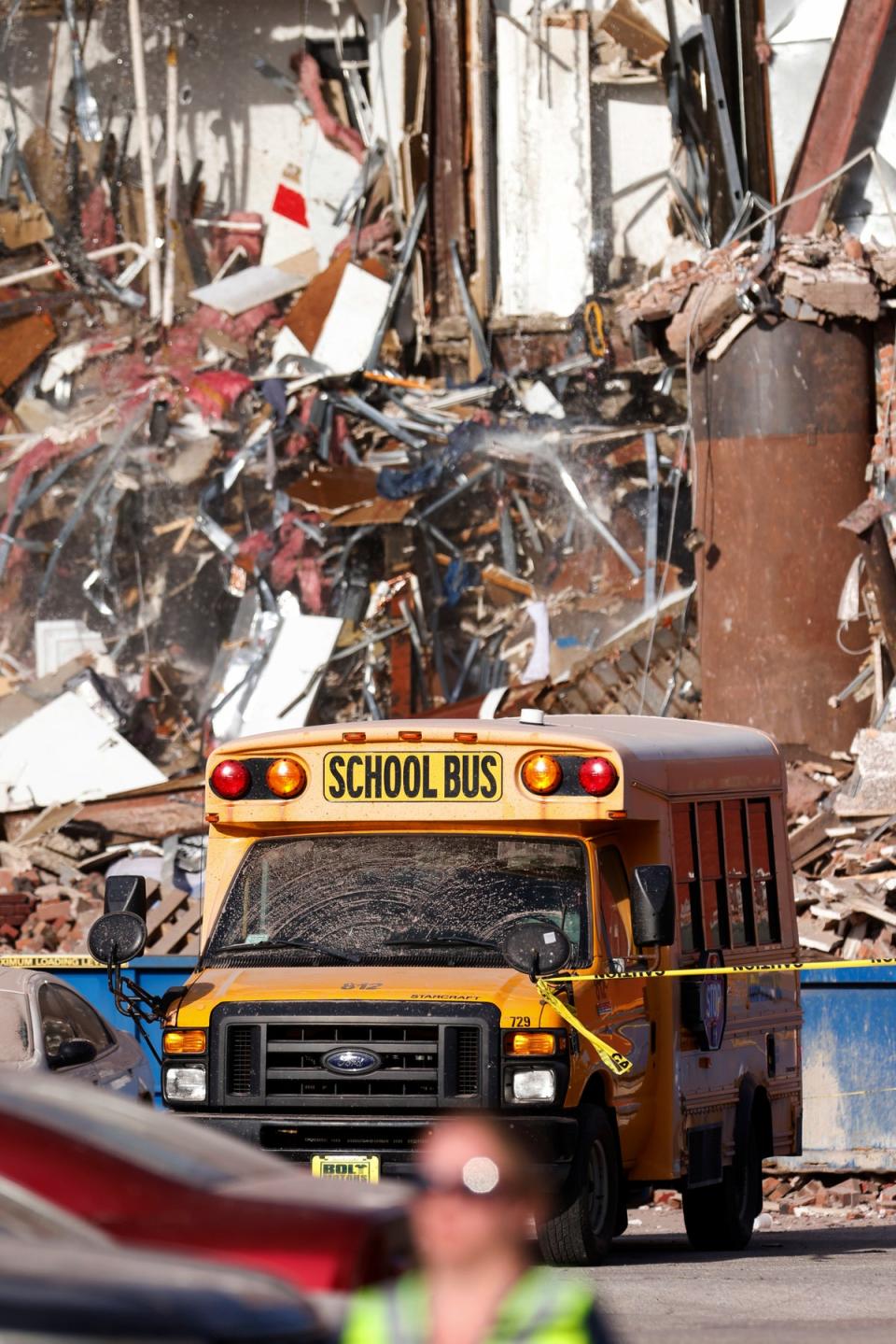 A school bus drives past the rubble after a building collapsed in Davenport, Iowa (Quad City Times)