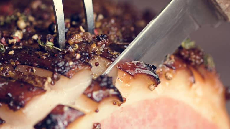 Knife cutting through baked ham