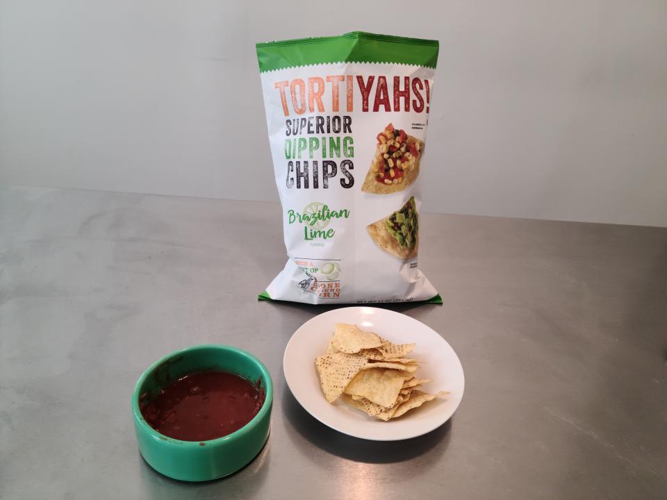 Tortiyahs bag behind plate of chips and bowl of red salsa.